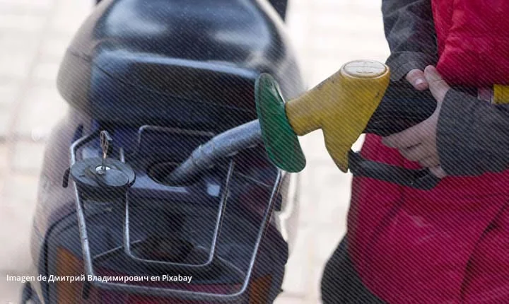 Persona llenando tanque de motocicleta en estación de gasolina