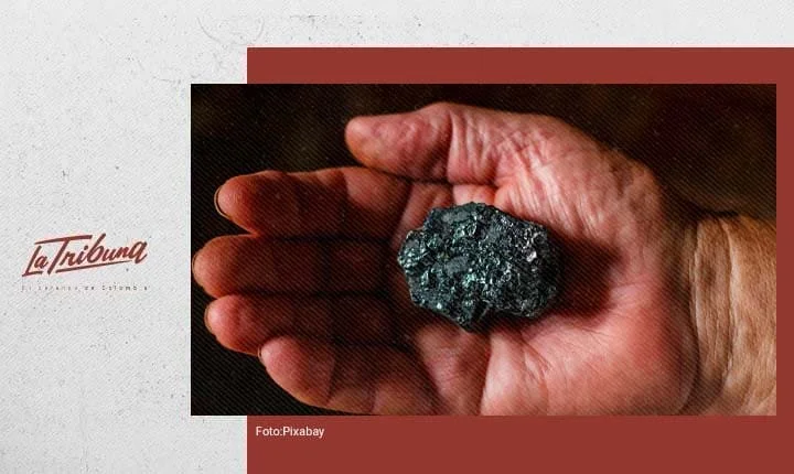 Mano sosteniendo una roca mineral oscura, símbolo de la minería en Colombia