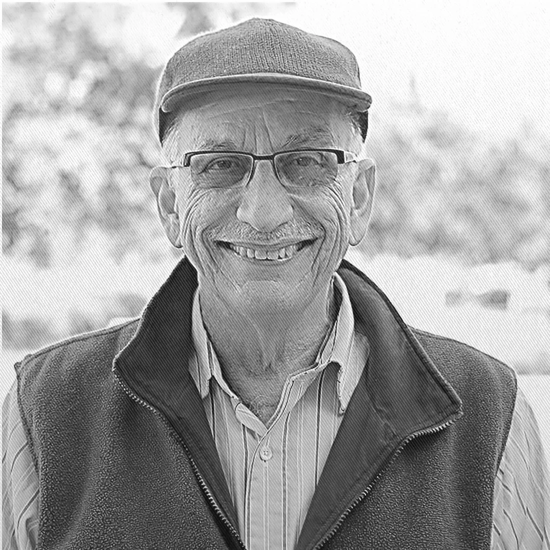 Raúl Fernández sonríe con gafas y gorra en retrato en blanco y negro