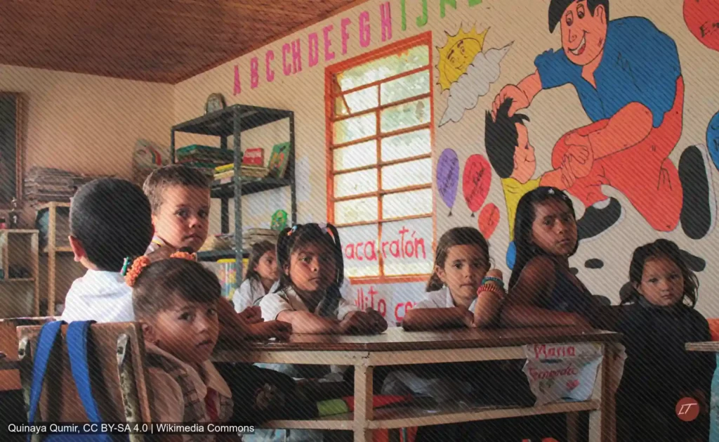 Estudiantes sentados en aula rural con mural infantil en la pared
