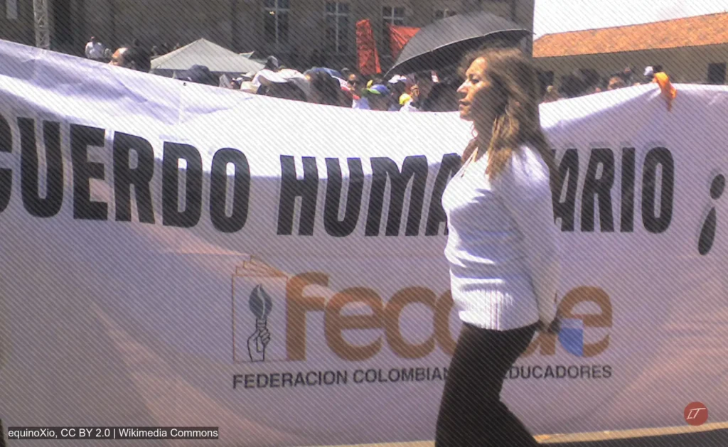 Mujer camina frente a pancarta de Fecode en una movilización