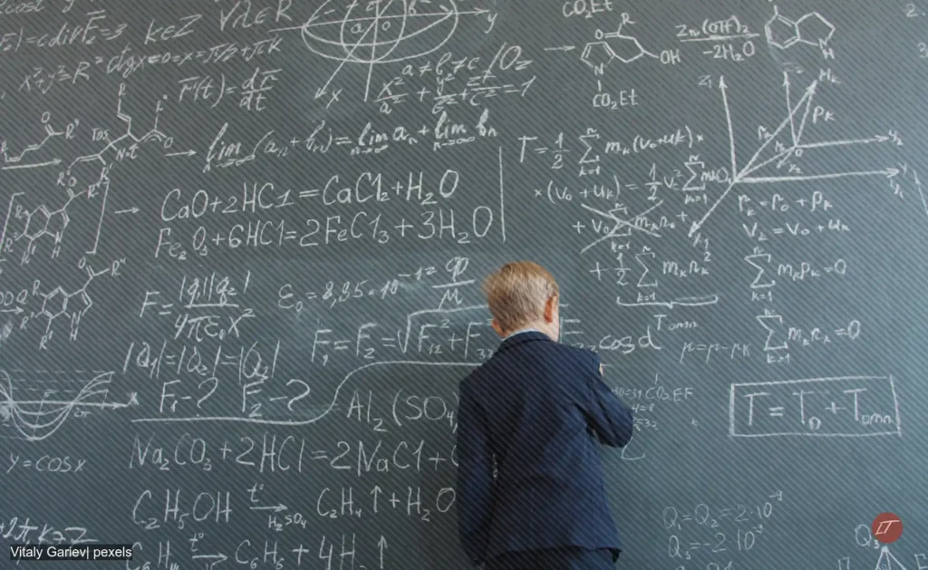 Niño escribe en tablero lleno de fórmulas matemáticas y científicas