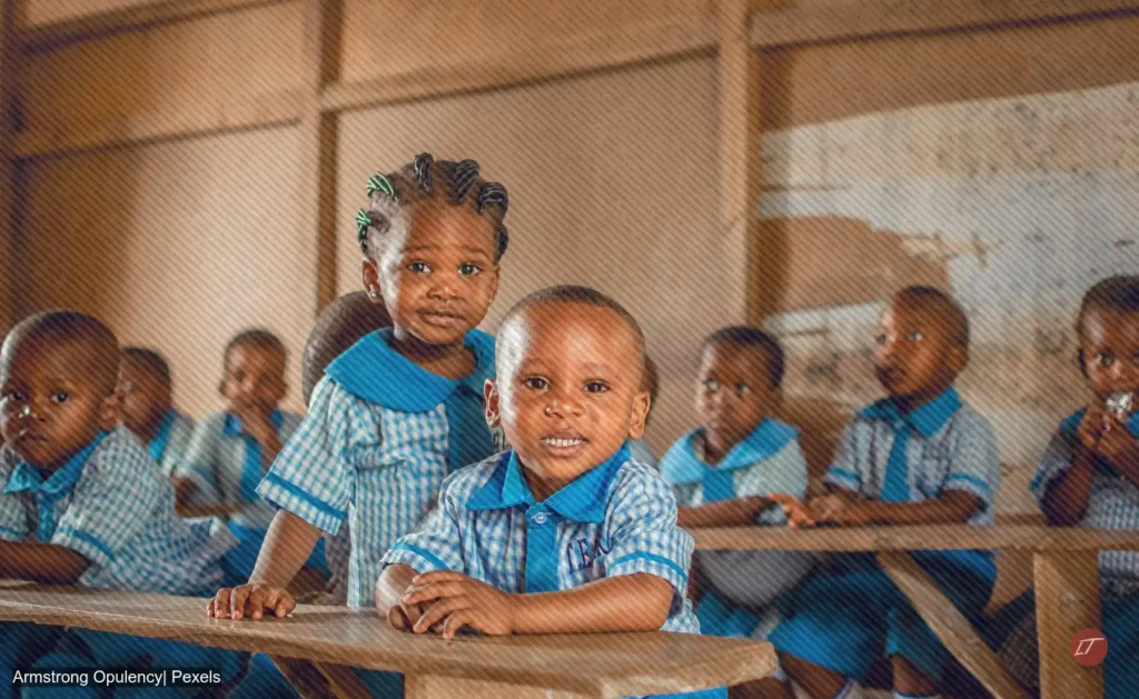 Niños con uniforme azul permanecen sentados en un salón de clase