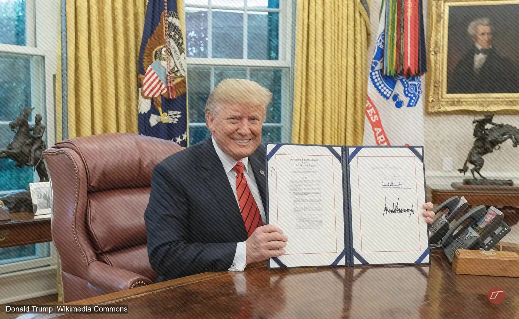 Donald Trump sonríe mientras muestra un documento firmado en el Despacho Oval