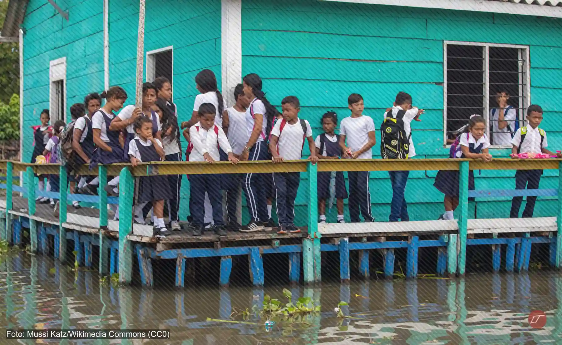 Estudiantes uniformados en el corredor de una escuela sobre pilotes en el agua, Colombia