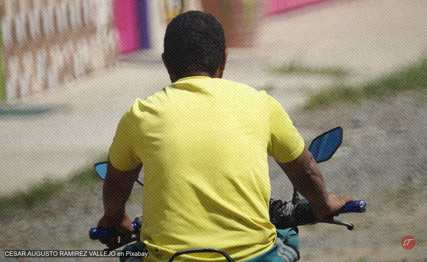 Persona con camiseta amarilla conduce una motocicleta por una calle, vista de espaldas